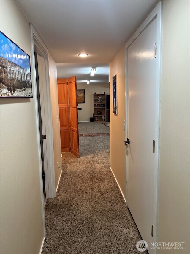 hallway with carpet flooring and baseboards