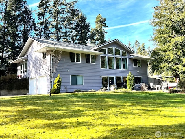 rear view of house with a garage, a chimney, and a lawn