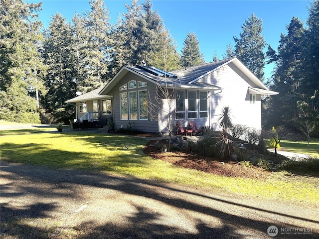 exterior space featuring a front lawn and roof mounted solar panels