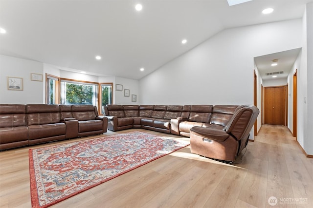 living room with vaulted ceiling with skylight and light hardwood / wood-style floors