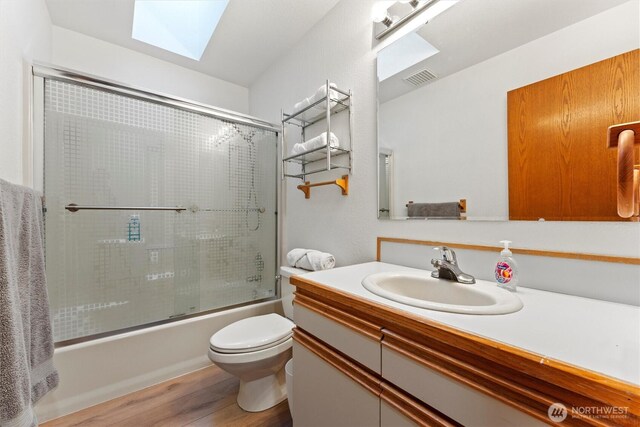 9447 Vernal Ave SE, Moses Lake, WA 98837 - full bathroom with enclosed tub / shower combo, a skylight, vanity, wood-type flooring, and toilet