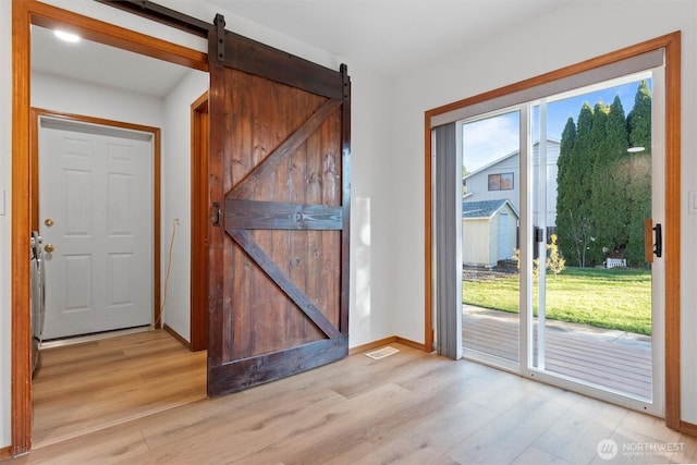 9447 Vernal Ave SE, Moses Lake, WA 98837 - doorway to outside with a barn door, a healthy amount of sunlight, and light wood-type flooring