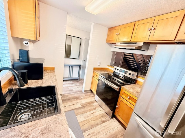 kitchen featuring appliances with stainless steel finishes, light hardwood / wood-style floors, sink, and a textured ceiling