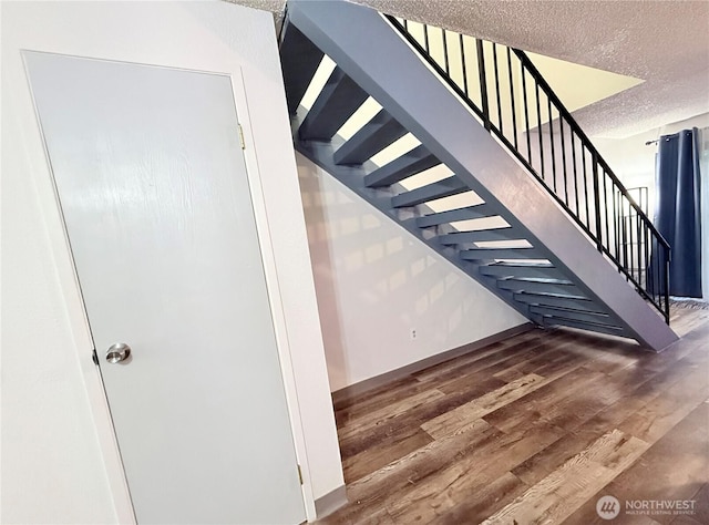 stairs featuring hardwood / wood-style flooring and a textured ceiling