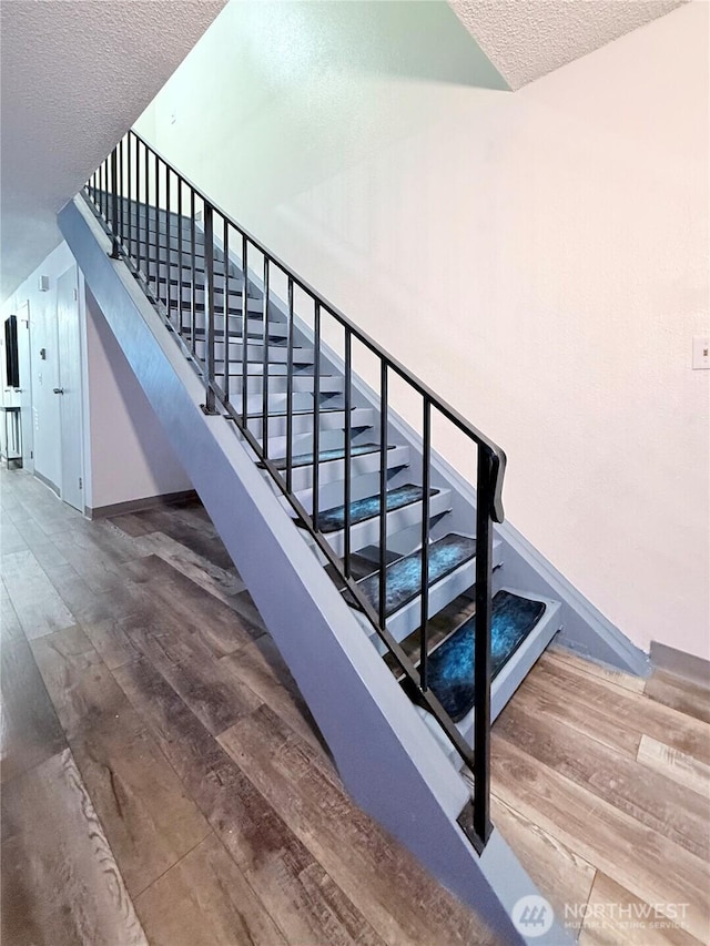 stairway featuring hardwood / wood-style floors and a textured ceiling