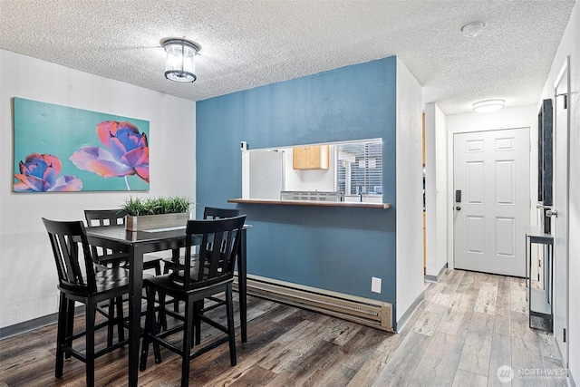 dining room with wood-type flooring and a textured ceiling