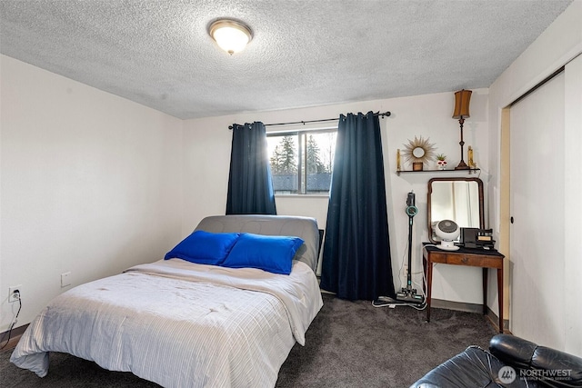 bedroom with dark carpet and a textured ceiling