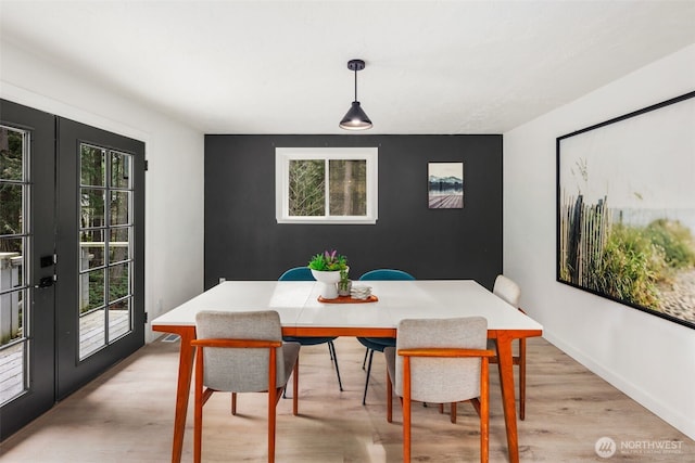 dining space with light wood-type flooring and french doors