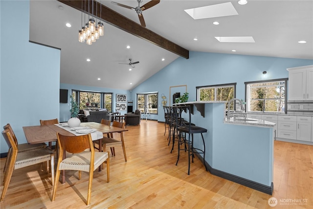 dining room with sink, beam ceiling, a wealth of natural light, and light hardwood / wood-style floors