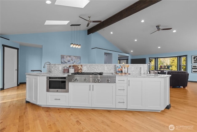 kitchen with appliances with stainless steel finishes, white cabinetry, sink, hanging light fixtures, and ceiling fan