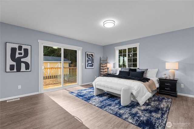 bedroom featuring wood-type flooring, multiple windows, and access to outside