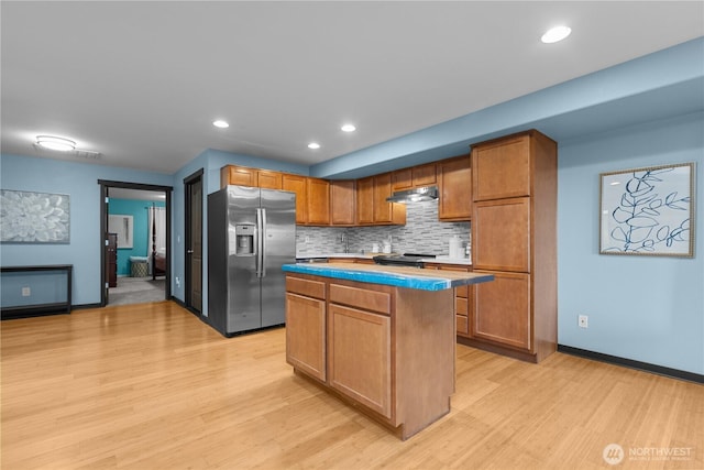 kitchen with backsplash, light hardwood / wood-style floors, a center island, and appliances with stainless steel finishes