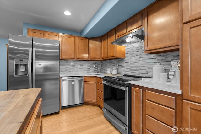 kitchen with backsplash, light hardwood / wood-style flooring, sink, and appliances with stainless steel finishes