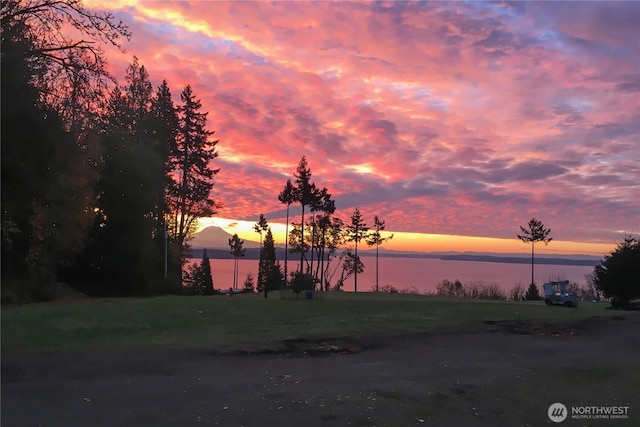 yard at dusk featuring a water view