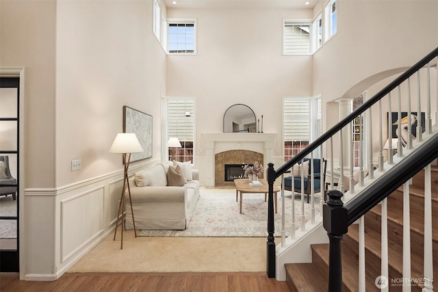 living room with hardwood / wood-style floors, a towering ceiling, and a premium fireplace