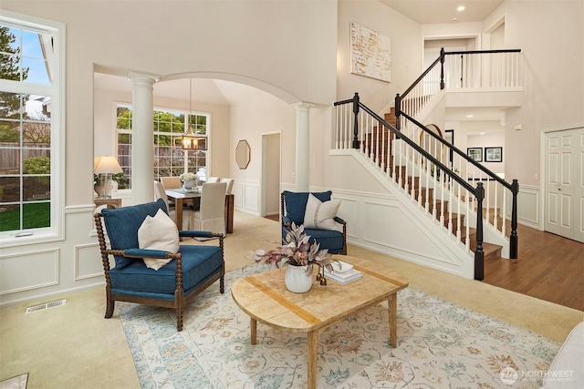 living room featuring decorative columns, a towering ceiling, and an inviting chandelier