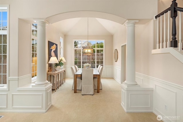 dining area featuring a notable chandelier, light colored carpet, and decorative columns