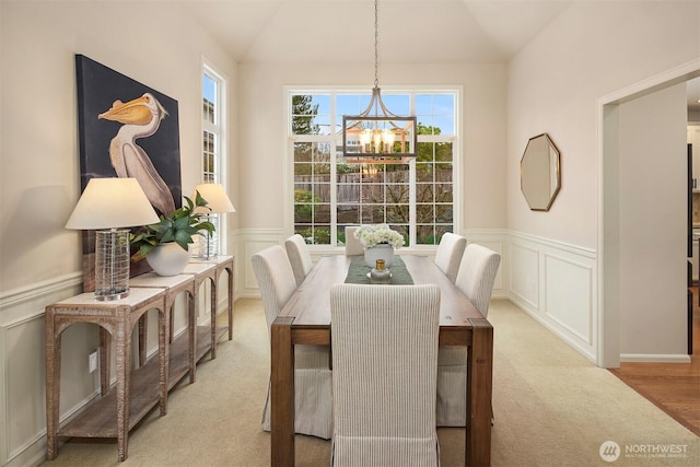 dining room with an inviting chandelier, lofted ceiling, and light carpet