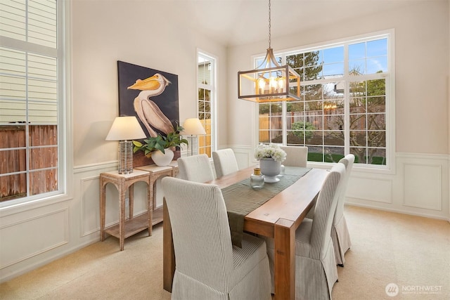 dining space with light carpet and a chandelier