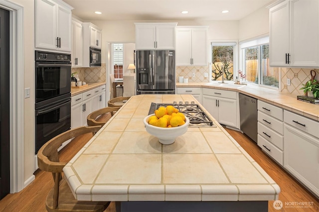 kitchen featuring white cabinetry, tile countertops, and black appliances