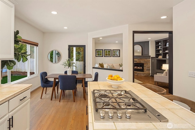 dining room featuring a stone fireplace, light hardwood / wood-style flooring, and built in features