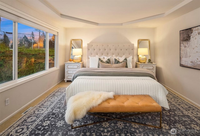 carpeted bedroom featuring a raised ceiling and multiple windows