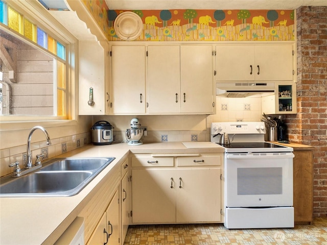 kitchen with sink, electric range, cream cabinetry, and backsplash