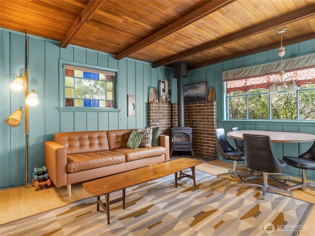 living room with wooden ceiling, beam ceiling, light hardwood / wood-style floors, and a wood stove