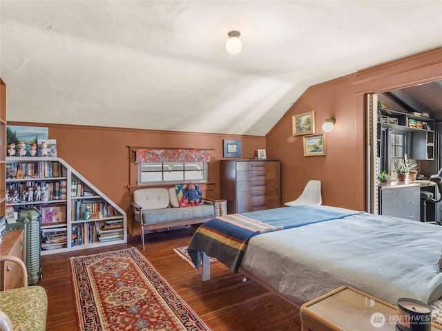 bedroom featuring lofted ceiling, dark hardwood / wood-style flooring, and wood walls