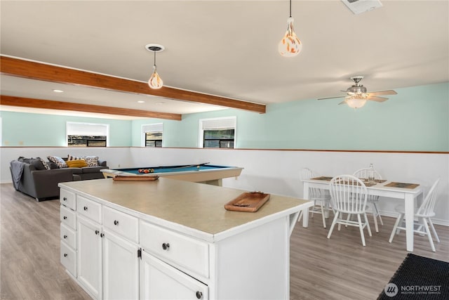 kitchen with hanging light fixtures, white cabinetry, a kitchen island, and beamed ceiling