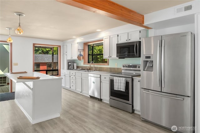 kitchen featuring white cabinetry, sink, hanging light fixtures, light hardwood / wood-style floors, and stainless steel appliances