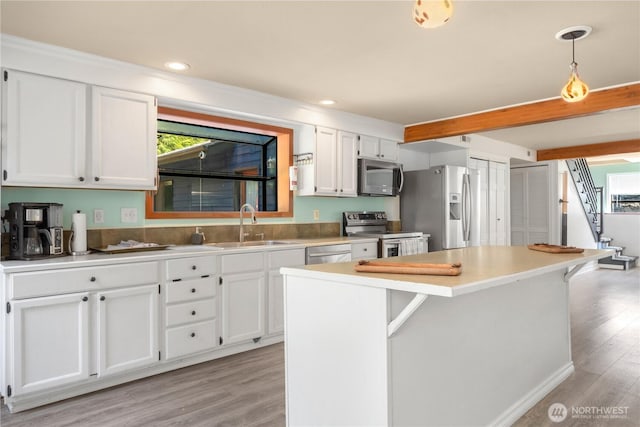 kitchen featuring sink, a breakfast bar area, white cabinets, hanging light fixtures, and stainless steel appliances