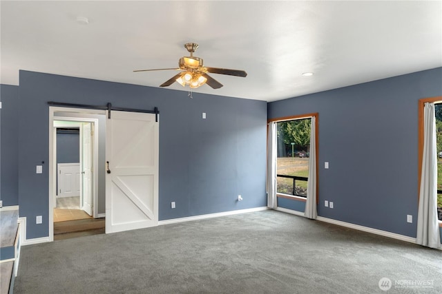 carpeted spare room featuring ceiling fan and a barn door