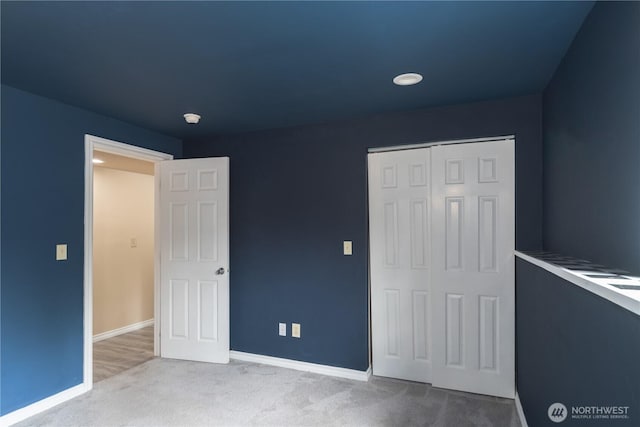 unfurnished bedroom with light colored carpet and a closet