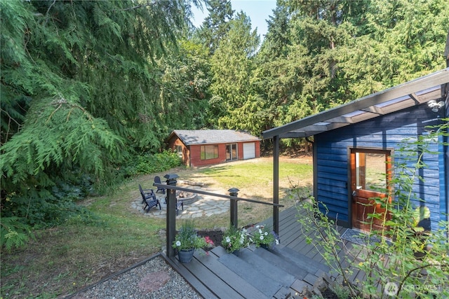 deck with a garage, an outbuilding, and a lawn