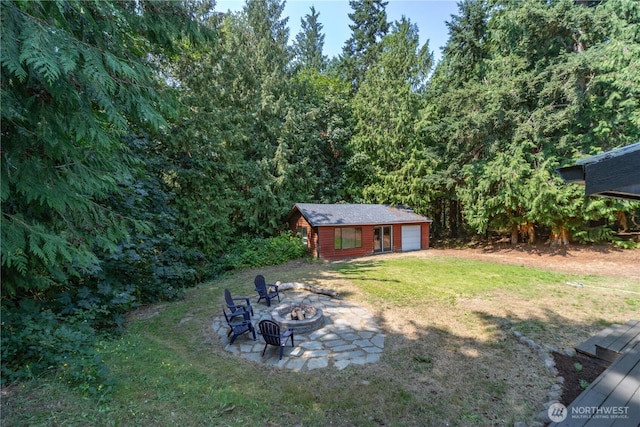 view of yard featuring an outbuilding, a garage, and a fire pit