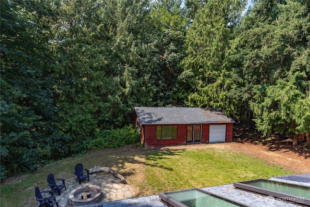 view of outdoor structure featuring a yard, a fire pit, and a garage