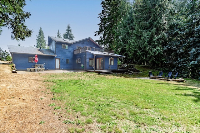 rear view of property featuring a balcony, a patio, and a lawn