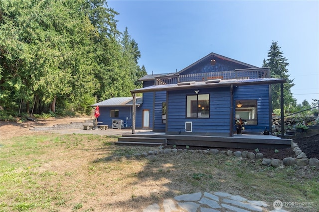 back of property featuring a wooden deck, a patio area, and a lawn