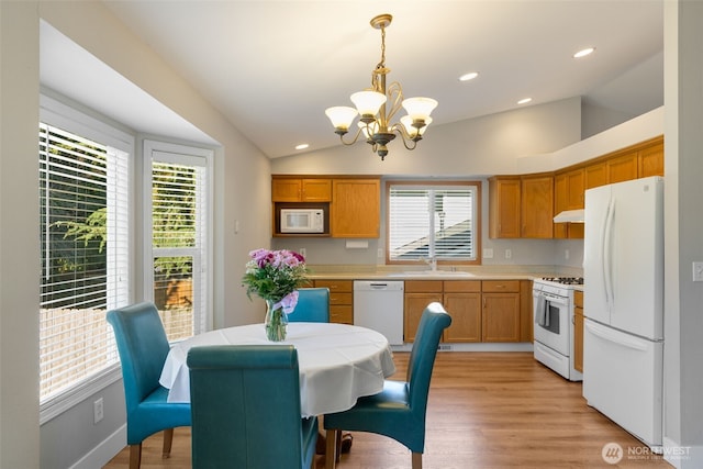 kitchen with pendant lighting, sink, white appliances, light hardwood / wood-style floors, and vaulted ceiling