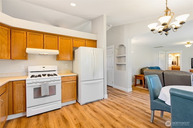 kitchen with built in shelves, vaulted ceiling, hanging light fixtures, white appliances, and light hardwood / wood-style floors