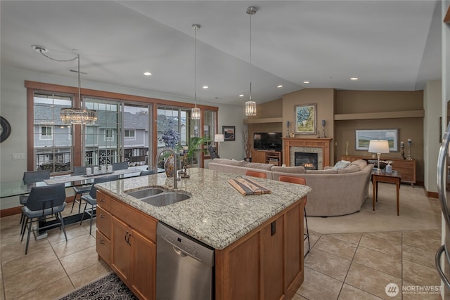 kitchen featuring dishwasher, lofted ceiling, light stone counters, a glass covered fireplace, and a sink