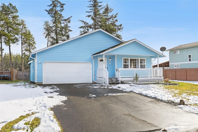 view of front of home with an attached garage, fence, aphalt driveway, and covered porch