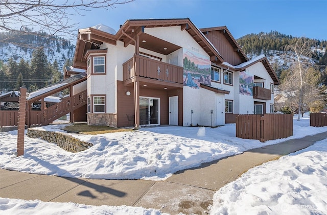 snow covered house featuring a balcony