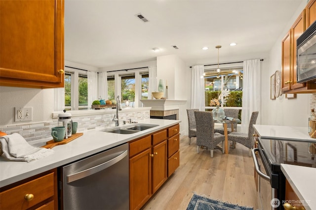 kitchen with visible vents, light wood-style flooring, a sink, stainless steel appliances, and backsplash