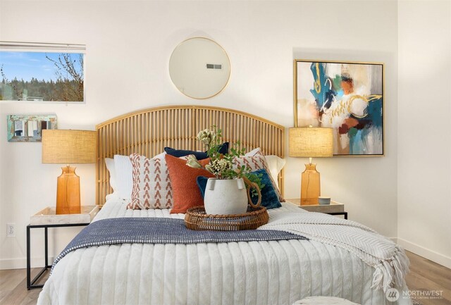 bedroom with visible vents, baseboards, and wood finished floors