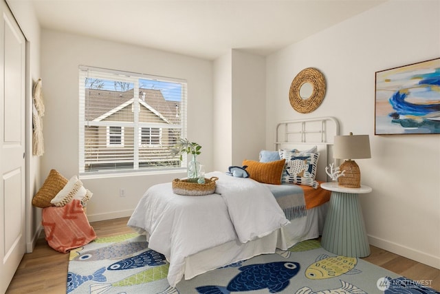 bedroom featuring light wood finished floors and baseboards