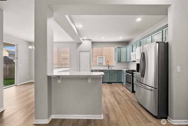 kitchen featuring kitchen peninsula, appliances with stainless steel finishes, a kitchen bar, and a wealth of natural light