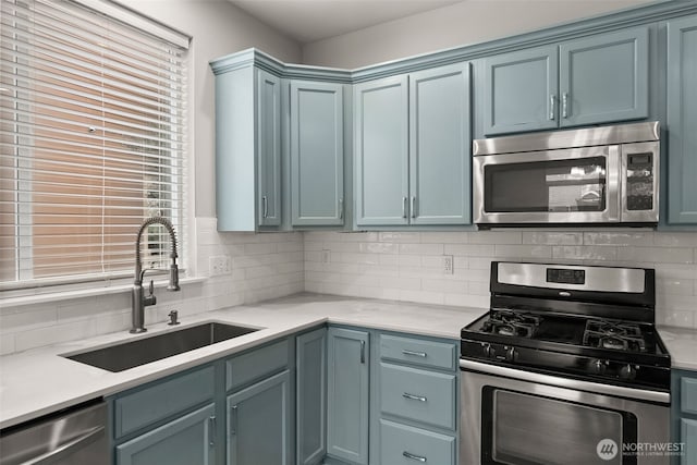 kitchen featuring sink, blue cabinetry, stainless steel appliances, and decorative backsplash