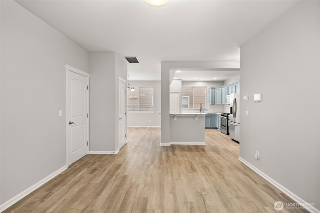 kitchen featuring a kitchen breakfast bar, light hardwood / wood-style flooring, sink, and stainless steel appliances